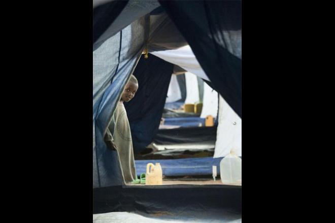 A boy peers from a tent in Dadaab refugee camp, Kenya, the largest refugee complex in the world. Dadaab was set up at the start of Somalia’s civil war in 1991. Designed to accommodate 90,000 Somali refugees, it is now home to nearly 500,000. Dadaab refugee camp, Kenya. Photo credit: Petterik Wiggers.