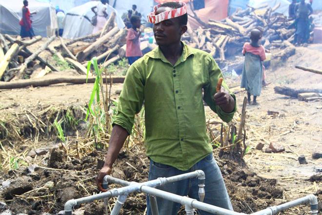 Un volontaire de la Croix-Rouge ougandaise prend de l’eau à des robinets installés par Oxfam dans l’une des cuisines du camp. Oxfam a placé des réservoirs d’eau souples et des robinets dans les cuisines du camp et au centre médical afin d’assurer que les Un volontaire de la Croix-Rouge ougandaise se sert à un point d’eau