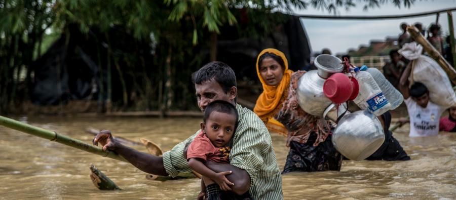 A father carries his son across a broken bridge on the edge of Balhukali camp, Bangladesh. Heavy rains flooded the areas where people had set up temporary shelters, forcing them to move to higher ground. Photo: Aurélie Marrier d’Unienville A father carries his son across a broken bridge on the edge of Balhukali camp, Bangladesh. Heavy rains flooded the areas where people had set up temporary shelters, forcing them to move to higher ground. Photo: Aurélie Marrier d’Unienville