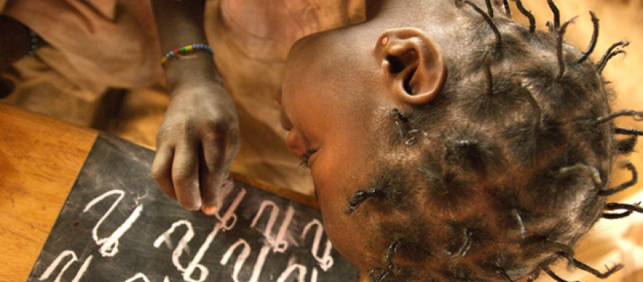 Girl writing letters with chalk on blackboard Burkina Faso