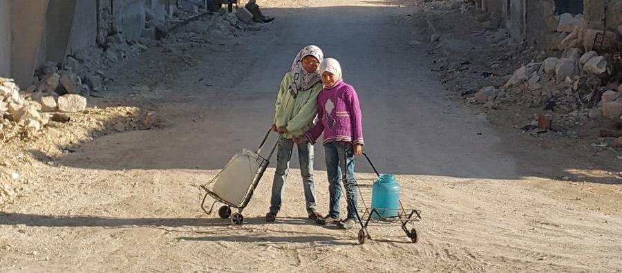 Alaa, 9, and Hayat 11, walk to a public water tank installed by Oxfam. The two girls and their families returned to Al-Sakhour area in East Aleppo after it was retaken by the Syrian army and its allies in December 2016. Photo: Feras Olabi/Oxfam Alaa, 9, and Hayat 11, walk to a public water tank. Photo: Feras Olabi/Oxfam