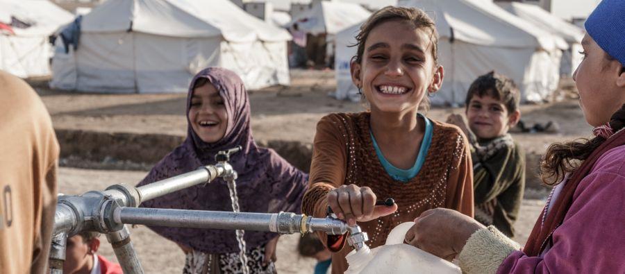 Children fill bottled with clean water at an Oxfam tap stand in Hassansham camp around 50km east of Mosul, Iraq. Credit: Tegid Cartwright/Oxfam Children fill bottled with clean water at a tap stand in Hassansham camp in east of Mosul, Iraq. Credit: Tegid Cartwright/Oxfam