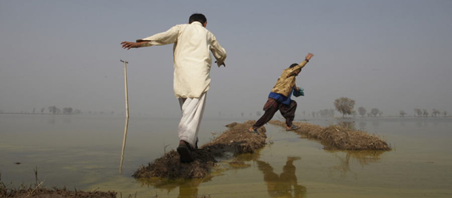 Cada nueva inundación ponía a millones de personas de nuevo en riesgo de sufrir enfermedades y desnutrición Two men avoid flooded land in fields, Pakistan