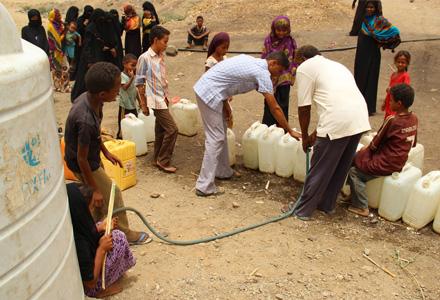 Yemen: People wait their turn to take share of the water for their families - Oxfam has provided water tanks and clean drinking water for the displaced.